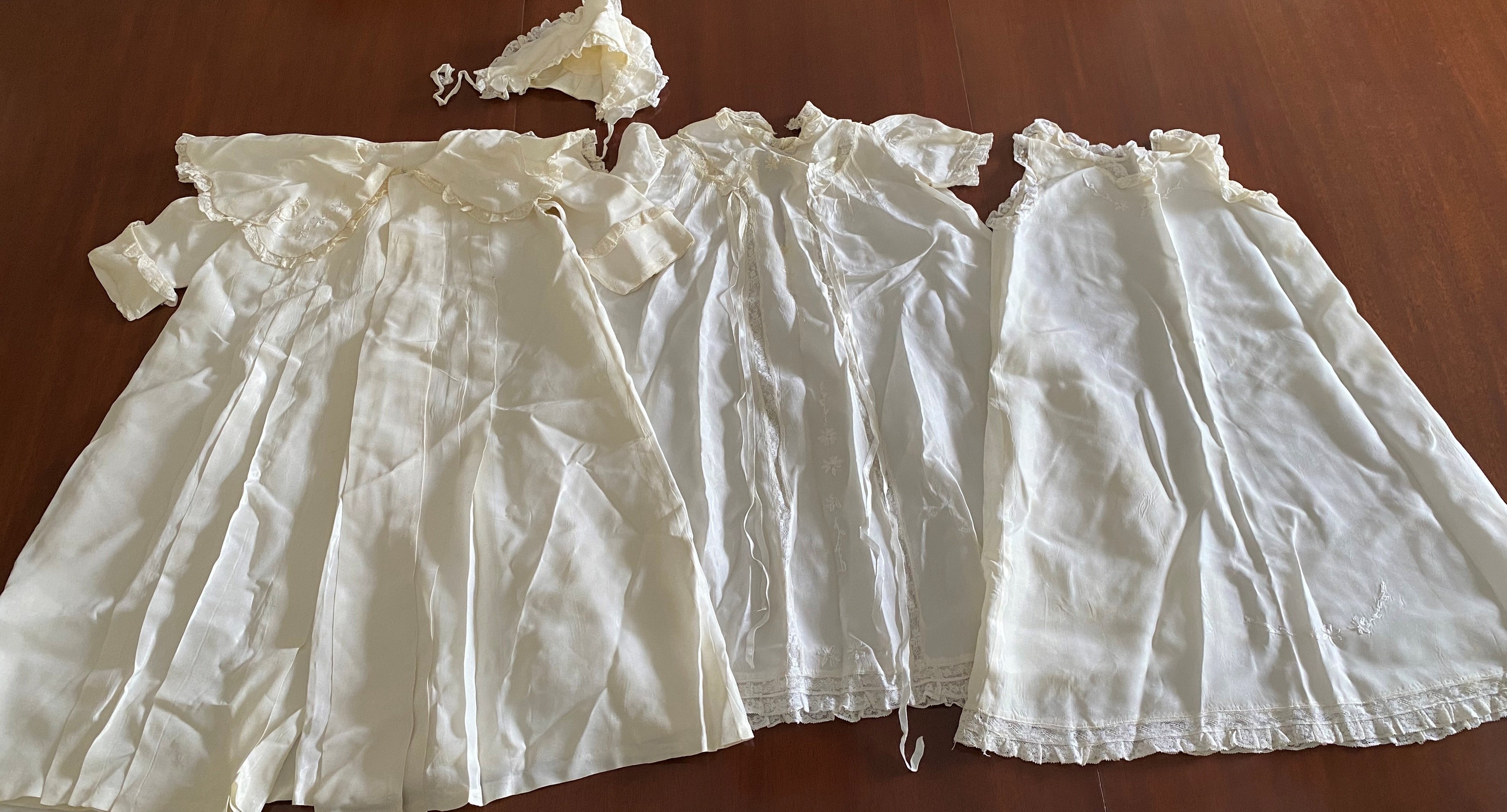 Three white baptismal gowns laid out together